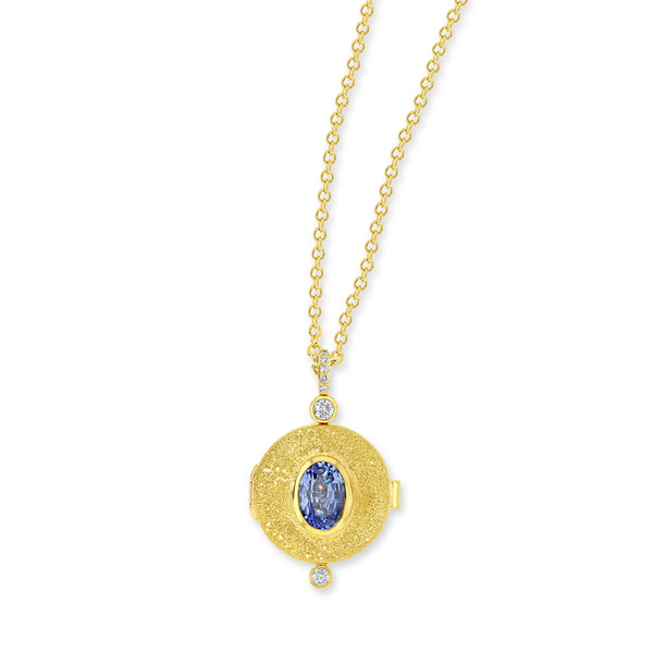 18k yellow gold locket necklace with diamond bail and bezel set white diamond. Center stone is an oval blue sapphire and the is a bezel set white diamond at the bottom of the locket
