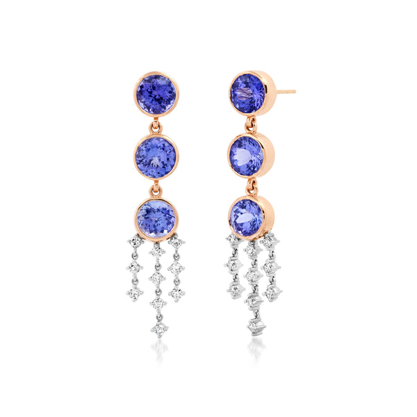 18k rose gold drop earrings with 3 round bezel set tanzanite stone. There are 3 droplets from the bottom tanzanite. The center drop has 4 white prong set diamonds and the 2 outside drops have 3 each. 